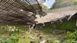 In this Aug. 11, 2020, file photo, provided by the Arecibo Observatory, shows the damage done by a broken cable that supported a metal platform, creating a 100-foot (30-meter) gash to the radio telescope's reflector dish in Arecibo, Puerto Rico.