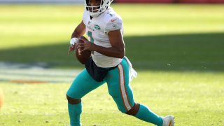 DENVER, COLORADO – NOVEMBER 22: Tua Tagovailoa #1 of the Miami Dolphins rolls out of the pocket during the first quarter against the Denver Broncos at Empower Field At Mile High on November 22, 2020 in Denver, Colorado. (Photo by Matthew Stockman/Getty Images)