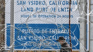 A commuter wearing a protective mask to avoid the spread of the COVID-19 walks towards the US-Mexico border at San Ysidro port of entry, in Tijuana, Baja California state, Mexico, on April 18, 2020.