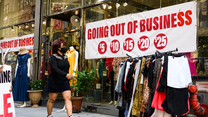 A pedestrian wearing a protective face mask walks by a going out of business sign displayed outside a retail store