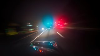 Car driving down road with red and blue lights