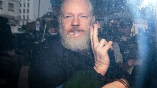 Julian Assange gestures to the media from a police vehicle on his arrival at Westminster Magistrates court on April 11, 2019 in London, England.