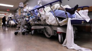 Patients lie on stretchers in a hallway in the overloaded Emergency Room at Providence St. Mary Medical Center amid a surge in COVID-19 patients in Southern California on January 5, 2021 in Apple Valley, California.