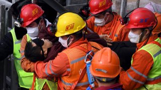 rescuers carry a miner who was trapped in a mine to an ambulance