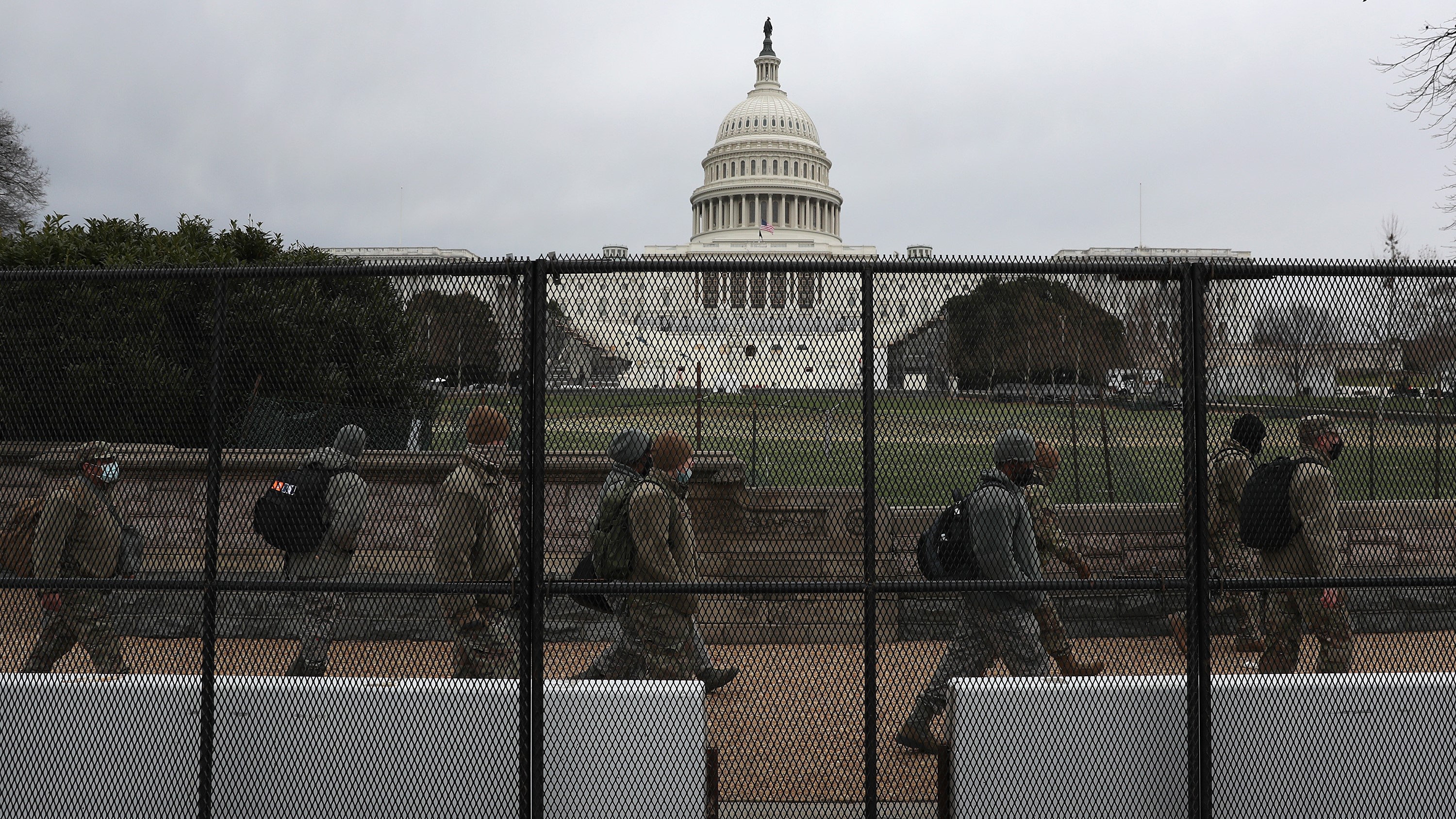 In this Jan. 8, 2021, file photo, members of the D.C. National Guard walk behind a fence placed around the U.S. Capitol building in Washington, D.C.