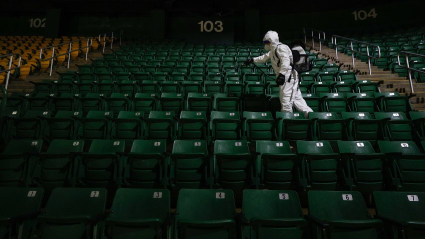 Alexander Espinoza of V&G Cleaning Services uses an electromagnetic sanitizer with hospital-grade disinfectant to sterilize the George Mason Patriots men's basketball spectator seating bowl against the novel coronavirus after their men's NCAA basketball game against the La Salle Explorers at Eagle Bank Arena on January 13, 2021 in Fairfax, Virginia.