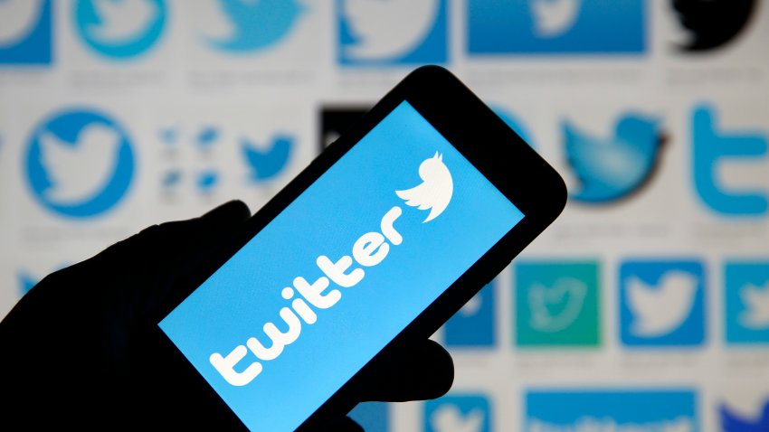 In this photo illustration, the Twitter logo is displayed on the screen of an iPhone in front of a computer screen displaying Twitter logos.