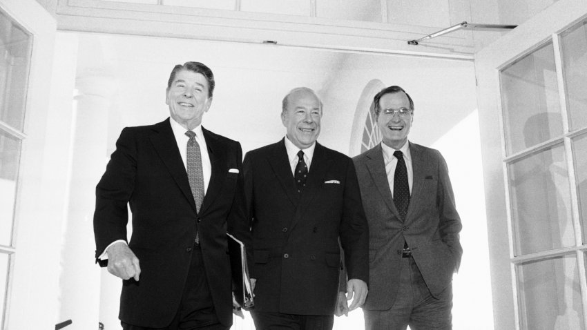 Secretary of State George Shultz, center, walks with President Ronald Reagan and Vice President George Bush