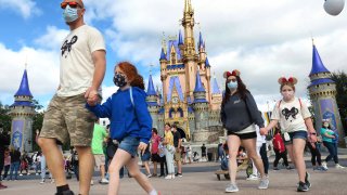 A masked family walks past Cinderella Castle in the Magic Kingdom in DisneyWorld