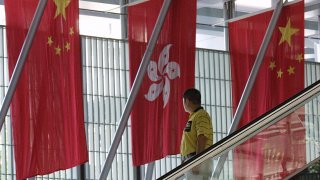 A man riding an escalator passes by flags of Hong Kong (C) and China.