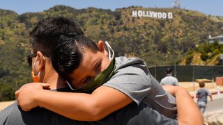 a father holds his son near the famed Hollywood sign during the coronavirus outbreak in Los Angeles