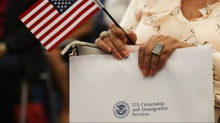 A person holds an American flag as they participate in a ceremony to become an American citizen during a U.S. Citizenship & Immigration Services naturalization ceremony at the Miami Field Office on August 17, 2018 in Miami, Florida.