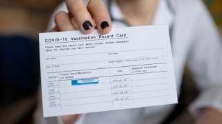 File photo showing a close up of a female doctor holding a COVID-19 Vaccination record card.