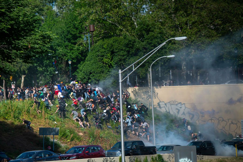 Protestors race up a hill after being shot by tear gas. The protesters said they were trapped in the cloud of gas by a fence, with nowhere to go. (Photo: Mark Makela / Getty Images)