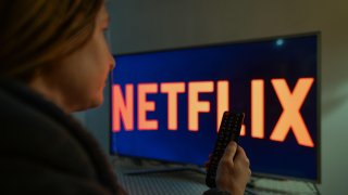 A picture of a woman starting Netflix on a TV inside her apartment.