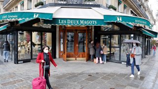 People walk past the closed iconic brasserie Les Deux Magots