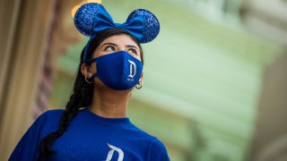 A woman wears a pair of Mickey Mouse ears and a matching mask.