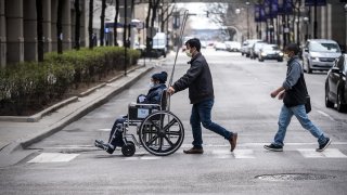 a man pushes a wheelchair towards Northwestern Memorial Hospital in Chicago, Illinois.