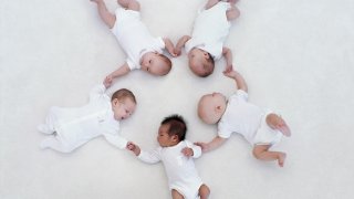 Five babies (0-3 months) lying on floor in circle (Digital Composite)