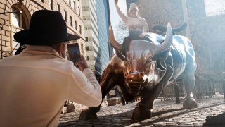 A man sits on the Wall street bull near the New York Stock Exchange (NYSE) on November 24, 2020 in New York City.