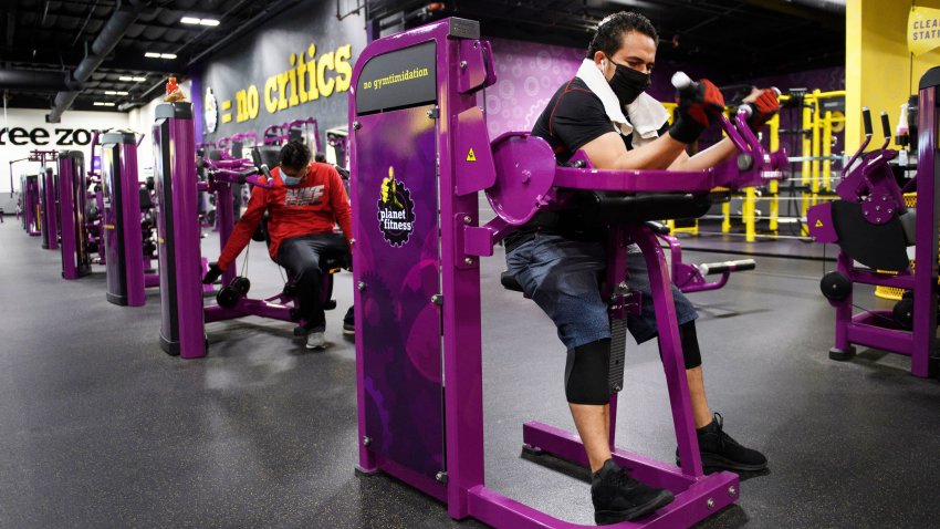 A customer wears a face mask as they lift weights while working out inside a Planet Fitness gym as the location reopens after being closed due to the Covid-19 pandemic, on March 16, 2021 in Inglewood, California.