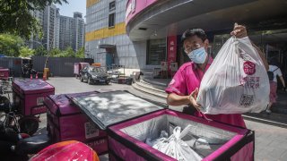 A driver packs delivery orders into the back of an electric motorcycle outside a Missfresh warehouse.