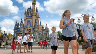 Guests walk past Cinderella Castle at the Magic Kingdom at Walt Disney World, in Lake Buena Vista, Fla., Monday, May 17, 2021, after Disney Co. eased face mask requirements over the weekend. Guests are allowed to go maskless in outdoor areas of the parks. Indoor attractions, shops and Disney transportation at the resort all still require masks. (Joe Burbank/Orlando Sentinel via AP)