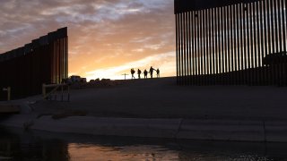 A pair of migrant families from Brazil pass through a gap in the border wall to reach the United States after crossing from Mexico in Yuma, Ariz., Thursday, June 10, 2021, to seek asylum. The families are part of an influx of asylum-seekers entering the U.S. in the Yuma area from South America and other continents.