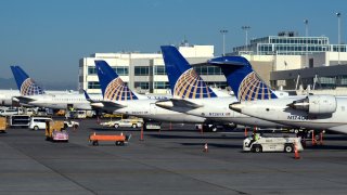 A row of United Airlines passenger planes parked at gates at Denver International Airport in Denver, Colorado.