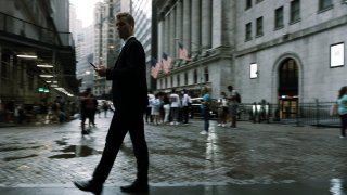 People walk along Wall Street in the rain on July 08, 2021 in New York City.
