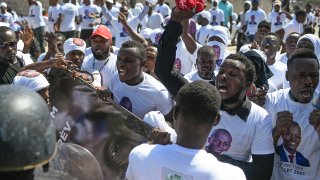 Supporters of slain Haitian President Jovenel Moise are blocked from attending Moise's funeral outside the former leader's family home