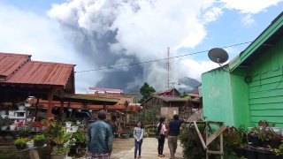 People watch as Mount Sinabung spews volcanic materials during an eruption in Karo, North Sumatra, Indonesia