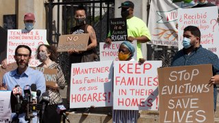 People from a coalition of housing justice groups hold signs protesting evictions
