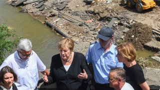 German Chancellor Angela Merkel (2ndL) and Rhineland-Palatinate State Premier Malu Dreyer (R) talk as they stand on a bridge during their visit in the flood-ravaged areas on July 18, 2021 in Schuld, near Bad Neuenahr-Ahrweiler, Rhineland-Palatinate state, western Germany. Extreme downpours caused devastating floods this week in Germany and other parts of western Europe devastating the region. The death toll across Germany and Belgium has risen to at least 180 as rescue workers continue their efforts and communities begin to clear the debris left by the receding waters.