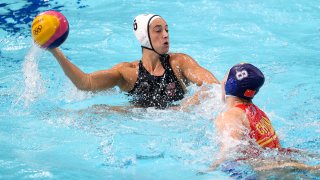 Maggie Steffens holds a water polo ball up in the pool.