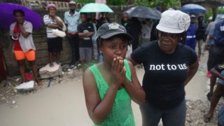 People watch the search for those who may be trapped under the earthquake rubble the morning after Tropical Storm Grace swept over Les Cayes