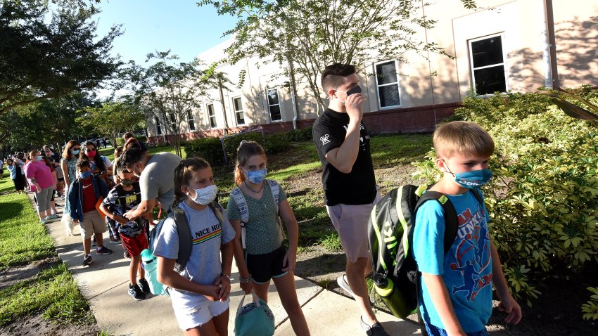 ORLANDO, FLORIDA, UNITED STATES – 2021/08/10: Students wearing face masks arrive with their parents on the first day of classes for the 2021-22 school year at Baldwin Park Elementary School. Due to the current surge in COVID-19 cases in Florida, Orange County public schools have implemented a face mask mandate for students for 30 days unless a parent chooses to opt out of the requirement. (Photo by Paul Hennessy/SOPA Images/LightRocket via Getty Images)