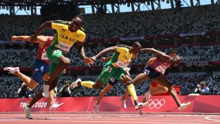Jamaica's Hansle Parchment (L) crosses the finish line to win ahead of second-placed USA's Grant Holloway (R) and third-placed Jamaica's Ronald Levy (C) in the men's 110m hurdles final during the Tokyo 2020 Olympic Games