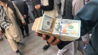 A person shows US dollars outside an exchange office, remained close since August 15th, following their reopening after Taliban takeover on September 04, 2021 in Kabul, Afghanistan.