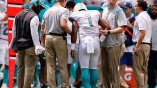 MIAMI GARDENS, FLORIDA – SEPTEMBER 19: Quarterback Tua Tagovailoa #1 of the Miami Dolphins is helped off the field in the first half of the game against the Buffalo Bills at Hard Rock Stadium on September 19, 2021 in Miami Gardens, Florida. (Photo by Michael Reaves/Getty Images)