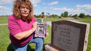Sharon Grover holds a photograph of her daughter, Rachael, over the gravesite at Fairview Cemetery