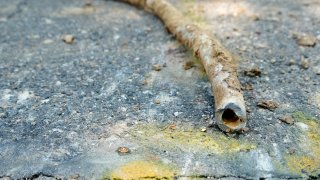 FILE – In this Thursday, June 17, 2021 file photo, a lead water service line from 1927 lies on the surface of a residential street after being removed in Denver.
