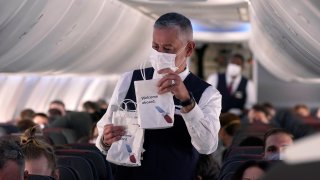 FILE - In this Dec. 2, 2020, file photo, an American Airlines flight attendant hands out snack bags aboard a Boeing 737 Max jet before taking off from Dallas Fort Worth airport in Grapevine, Texas. The Federal Aviation Administration say flight attendants should get more rest between shifts, proposing Thursday, Oct. 21, 2021, that airline cabin crew members get 10 straight hours of rest between shifts. That's up from nine.