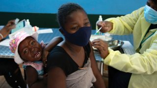 FILE — A baby cries on it's mother's back as the mother receives her Pfizer vaccine