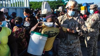 A woman, who is denied entry into the Dominican Republic, tries to put on her protective face mask