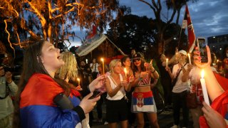 Supporters of Serbia's Novak Djokovic protest and sing with candles outside a quarantine facility where Djokovic is believed to be detained, in Melbourne, Australia, Thursday, Jan. 6, 2022. The Australian government has denied No. 1-ranked Djokovic entry to defend his title in the year's first tennis major and canceled his visa because he failed to meet the requirements for an exemption to the country's COVID-19 vaccination rules.