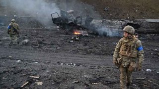 Ukrainian service members look for unexploded shells after a fighting with Russian raiding group in the Ukrainian capital of Kyiv in the morning of February 26, 2022, according to Ukrainian service personnel at the scene.