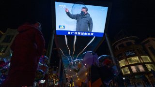 A balloon floats past a screen showing a news report on the Chinese President Xi Jinping attending the opening ceremony of the 2022 Winter Olympics in Beijing, China, Feb. 5, 2022.