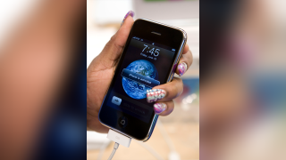 An Apple store employee activates an Apple iPhone 3G showing the "3G" symbol