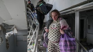 An injured pregnant woman walks downstairs in the damaged by shelling maternity hospital in Mariupol, Ukraine, Wednesday, March 9, 2022. A Russian attack has severely damaged a maternity hospital in the besieged port city of Mariupol, Ukrainian officials say.